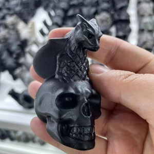 Macro shot of a hand holding a matte black obsidian dog figurine with skull details