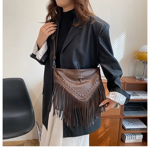 Détail du sac à bandoulière vintage marron à franges avec rivets et emblème de croix