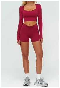 Dettaglio degli shorts da yoga a vita alta con incrocio a V e crop top a coste rosso bacca