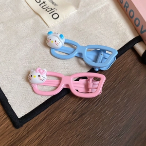Close-up of pink and blue cartoon cat glasses hair clips on a textured background