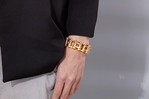 Detail of a bold golden 22mm bicycle chain bracelet worn on a male wrist