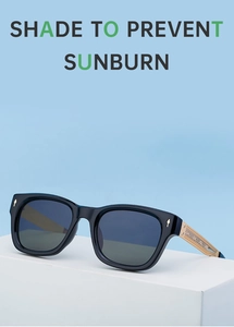 Detail of black sunglasses with intricate gold engraved metal temples on a stand