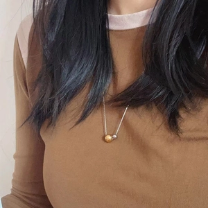 Detailed view of two-tone gold and silver bead pendants on a fine silver chain necklace