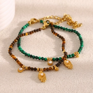 Detail of beaded bracelets featuring green malachite and tiger eye with Hamsa hand pendant