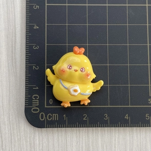 Detailed view of a 2.5cm cute yellow resin chicken charm on a black measuring mat