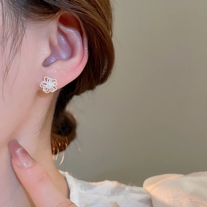 Close-up of elegant hollow flower stud earrings with a shimmering silver finish on model