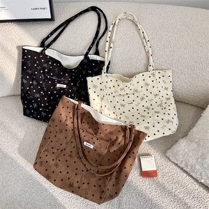 Detailed texture of corduroy tote bags with heart and bow prints in black, beige, and brown