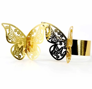 Detail of laser-cut butterfly napkin rings in polished gold and black metal finishes