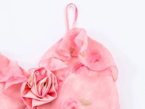 Detailansicht eines rosa Blumenkleides mit Rüschenausschnitt und 3D-Rosendekoration