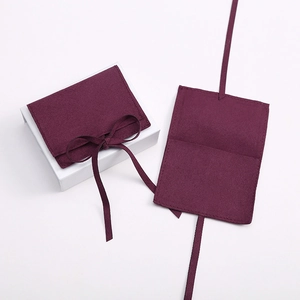 Macro view of burgundy velvet jewelry pouch with white gift box and matching ribbon tie