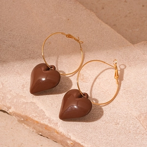Detailed view of brown acrylic heart charms hanging from large gold metal hoop earrings