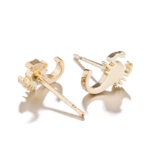 Detailed macro view of gold-plated scorpion stud earrings with a polished mirror finish