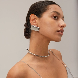 Close-up of a model wearing minimalist silver choker and large rectangular drop earrings