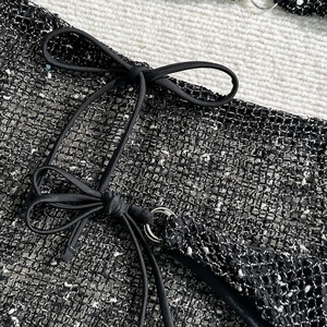 Macro detail of black and white mesh bikini cover-up with tie-string and silver ring buckle