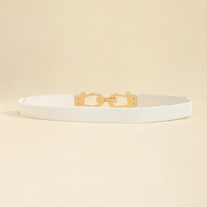 Detailed macro view of an interlocking gold metal buckle on a white elastic waistband