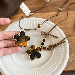 Close-up of tortoise shell flower pendant necklaces on a white ceramic plate
