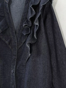 Detail of dark blue denim shirt featuring elegant ruffled trim and matching buttons