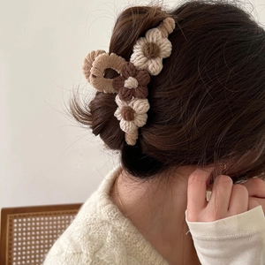 Detail of hand-crocheted brown and beige floral hair claw clip on female model