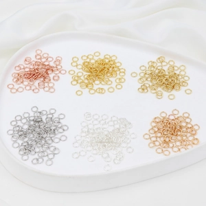 Close-up of DIY jewelry jump rings in various metal finishes on white background