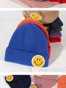 Close-up of ribbed knit beanie hats featuring various colors and iconic yellow smiley patch