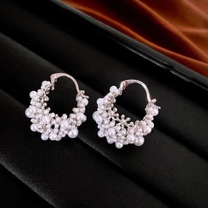 Detail view of gold-plated hoop earrings with clusters of white rice pearls