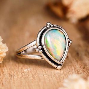 Détail macro de la bague vintage en argent avec opale irisée sur fond en bois