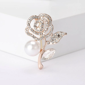 Close-up of golden rose brooch featuring a large pearl bud and shimmering rhinestone petals