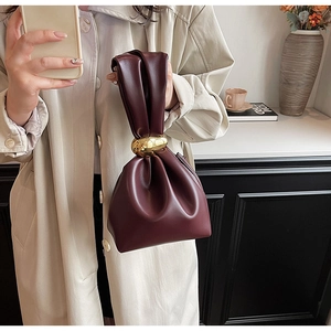 Detailed view of burgundy pleated dumpling handbag with elegant gold metal ring buckle