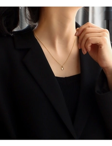 Close-up of golden oval pendant necklace with starburst engraving worn on model
