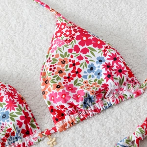 Detailed close-up of floral bikini top featuring vibrant prints and gold flower pendant