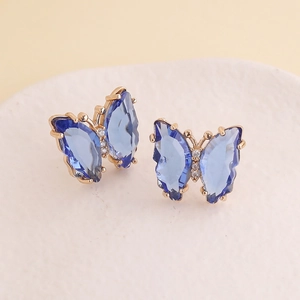 Close-up of golden butterfly earrings with dark blue wings and micro-pave diamond details