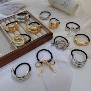 Close-up of assorted gold and silver metal charms on elastic hair ties in a wooden tray