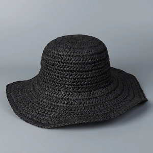 Detailed texture of black hand-woven straw wide-brim sun hat for beach vacation