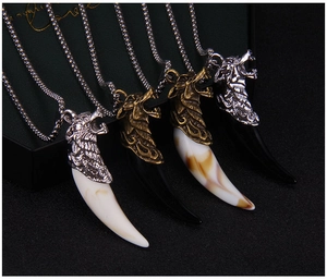 Detail of four stainless steel wolf tooth necklaces in silver and bronze metal finishes