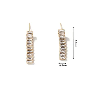 Close-up of golden fringe earrings with baguette-cut zircon stones measuring 3.2cm in length