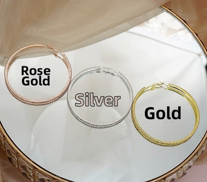 Detail of oversized hoop earrings in rose gold, silver and gold with rhinestone inlay