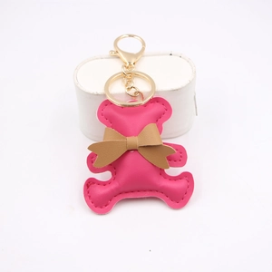 Close-up of pink PU leather bear keychain with brown bow and golden metal lobster clasp