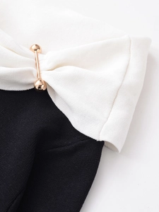 Detailed close-up of a knitting fabric with a golden spherical pin on contrast shoulder