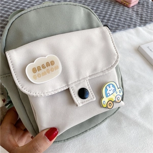 Détail du mini sac bandoulière en toile avec badges de dessin animé et texte FOMFOM