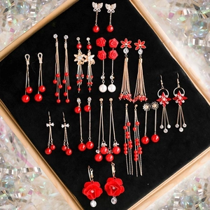 Macro shot of 14-pair set featuring festive red and gold tassel drop earrings in velvet tray