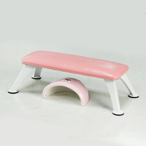 Pink leather manicure hand rest with UV LED nail lamp on marble surface close-up