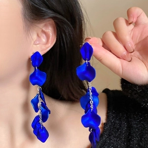Close-up of royal blue rose petal tassel earrings with long metallic chains on model