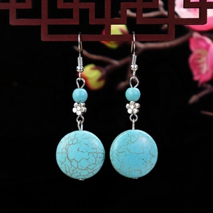 Macro shot of turquoise drop earrings with silver metal flower details and long hooks