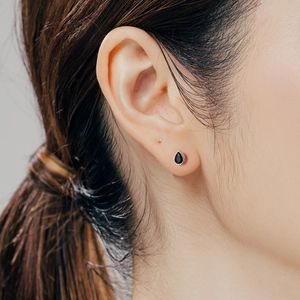 Elegant S999 sterling silver teardrop earring with black zircon shown on model ear