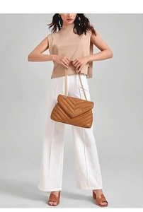 Detailed view of brown quilted leather bag with V-shaped stitching and golden chain strap