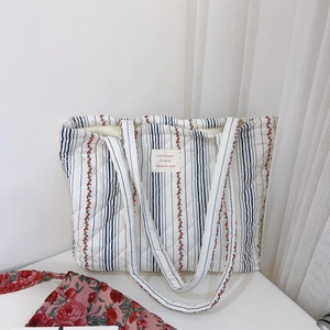 Détail du sac cabas matelassé à fleurs avec étiquette française et rayures bleues