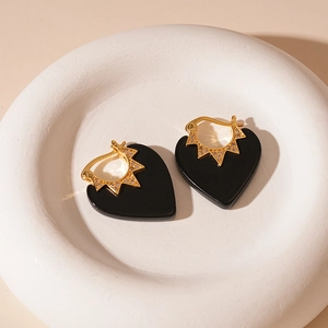 Détails de boucles d'oreilles cœur noir avec émail et plaqué or dans une coupe blanche