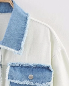 Close-up of denim jacket collar and pocket with frayed edges and contrast stitching