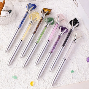 Set of 8 silver metal ballpoint pens filled with natural crystal stones on white background