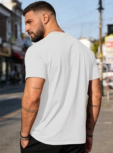 Outdoor street style view of men's plain white cotton t-shirt showing the back and side profile